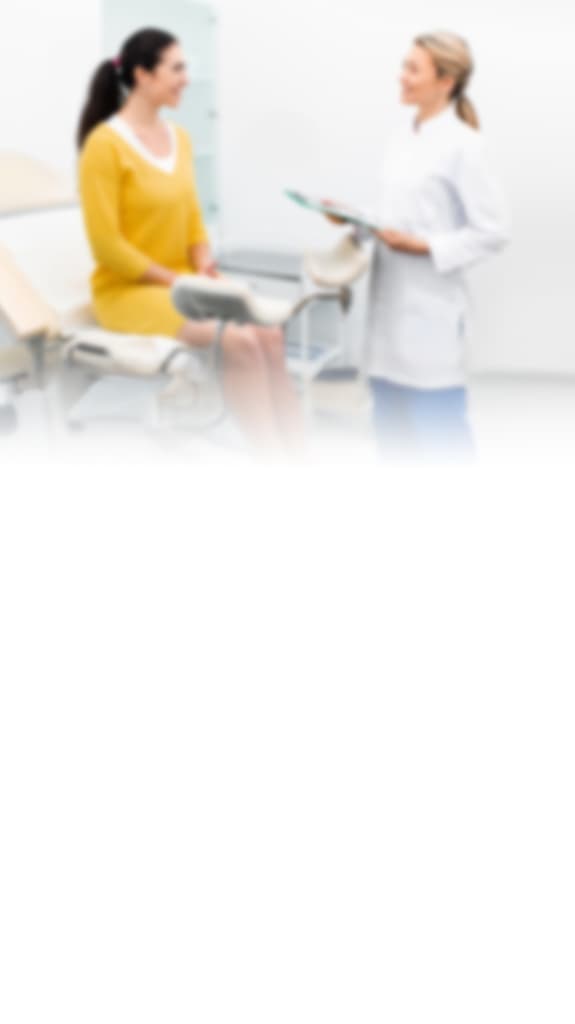 Frau spricht mit einer Gynäkologin im Untersuchungszimmer